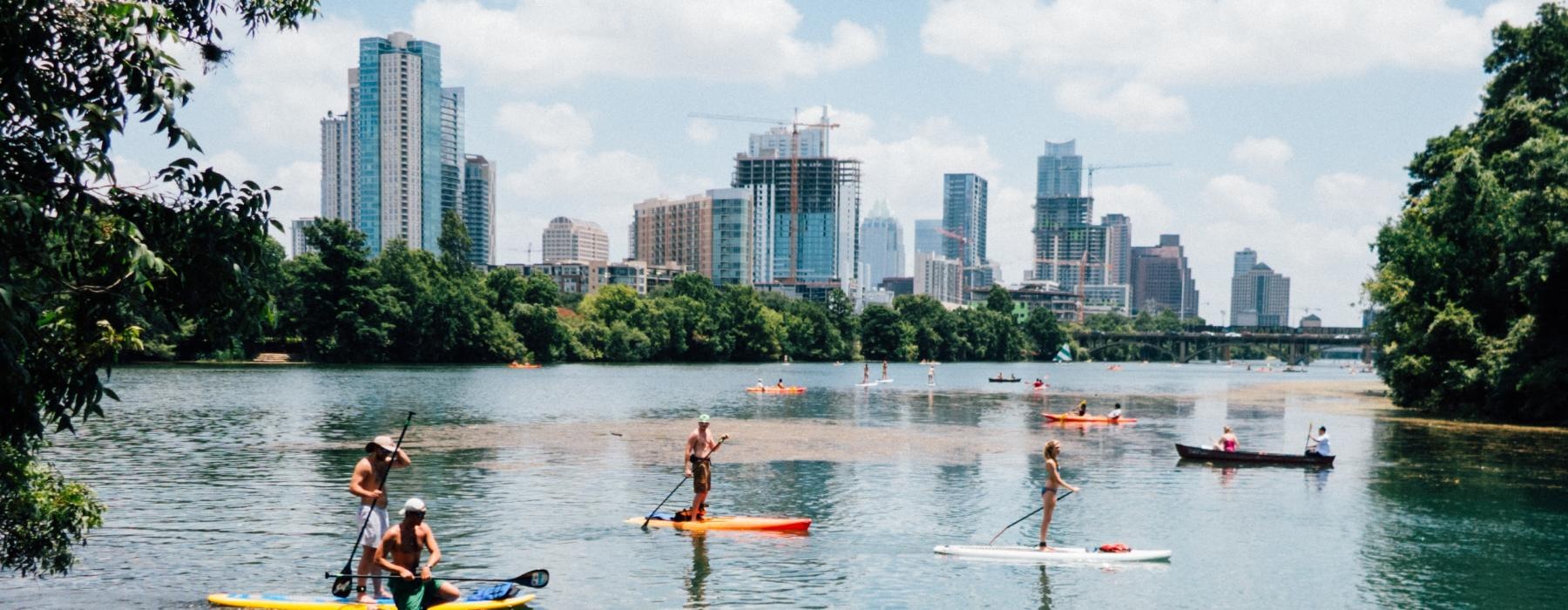 a group of people on paddle boards with a city in the background